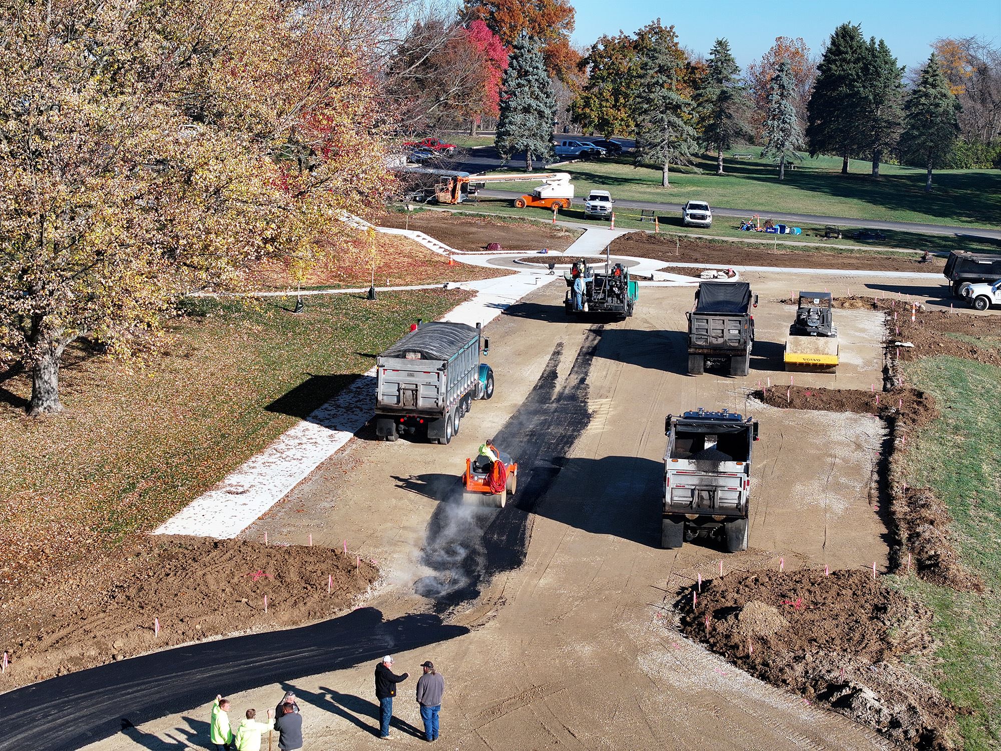 Trucks and rollers paving a new parking lot