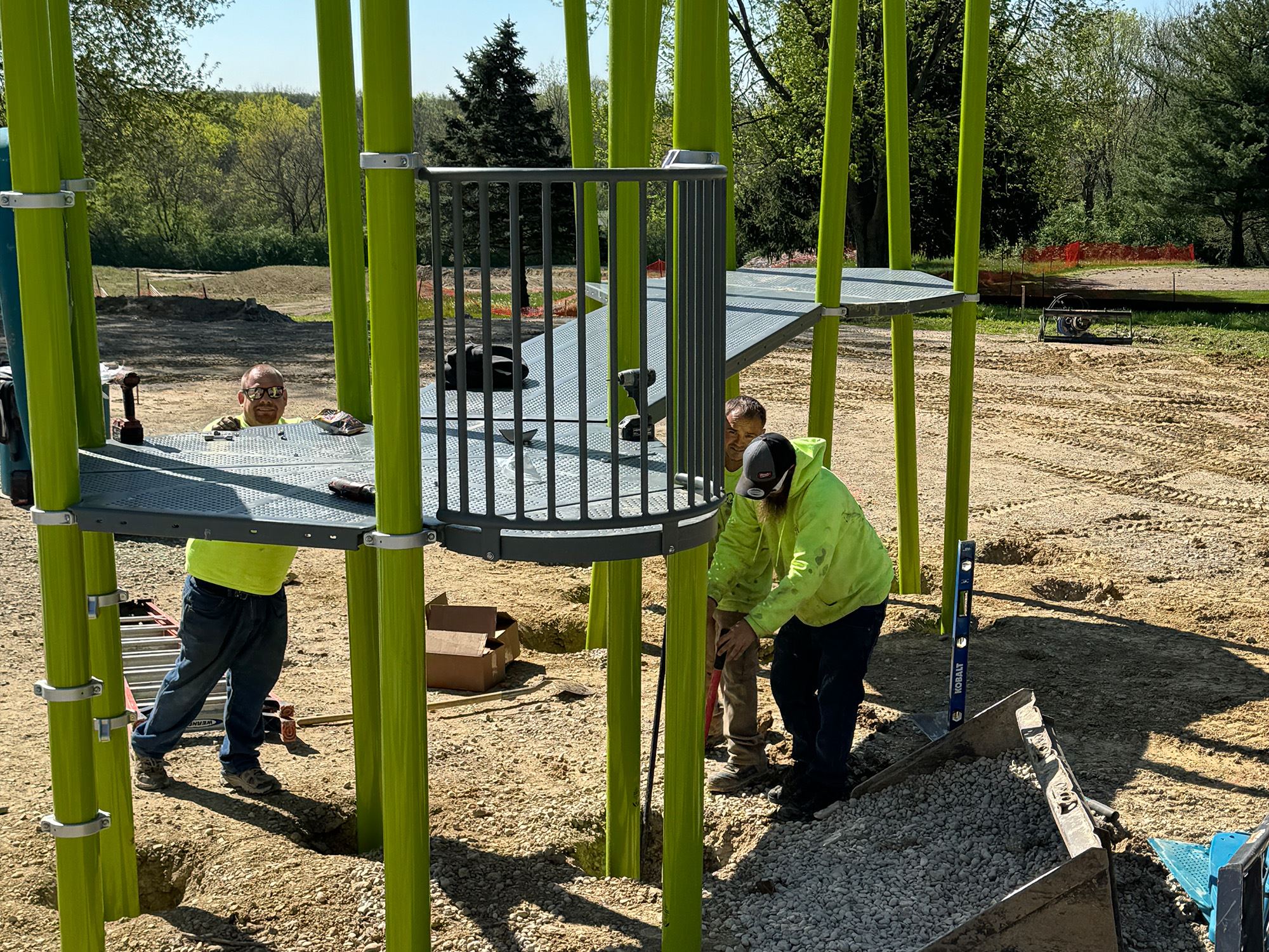 Workers installing bright green playground posts