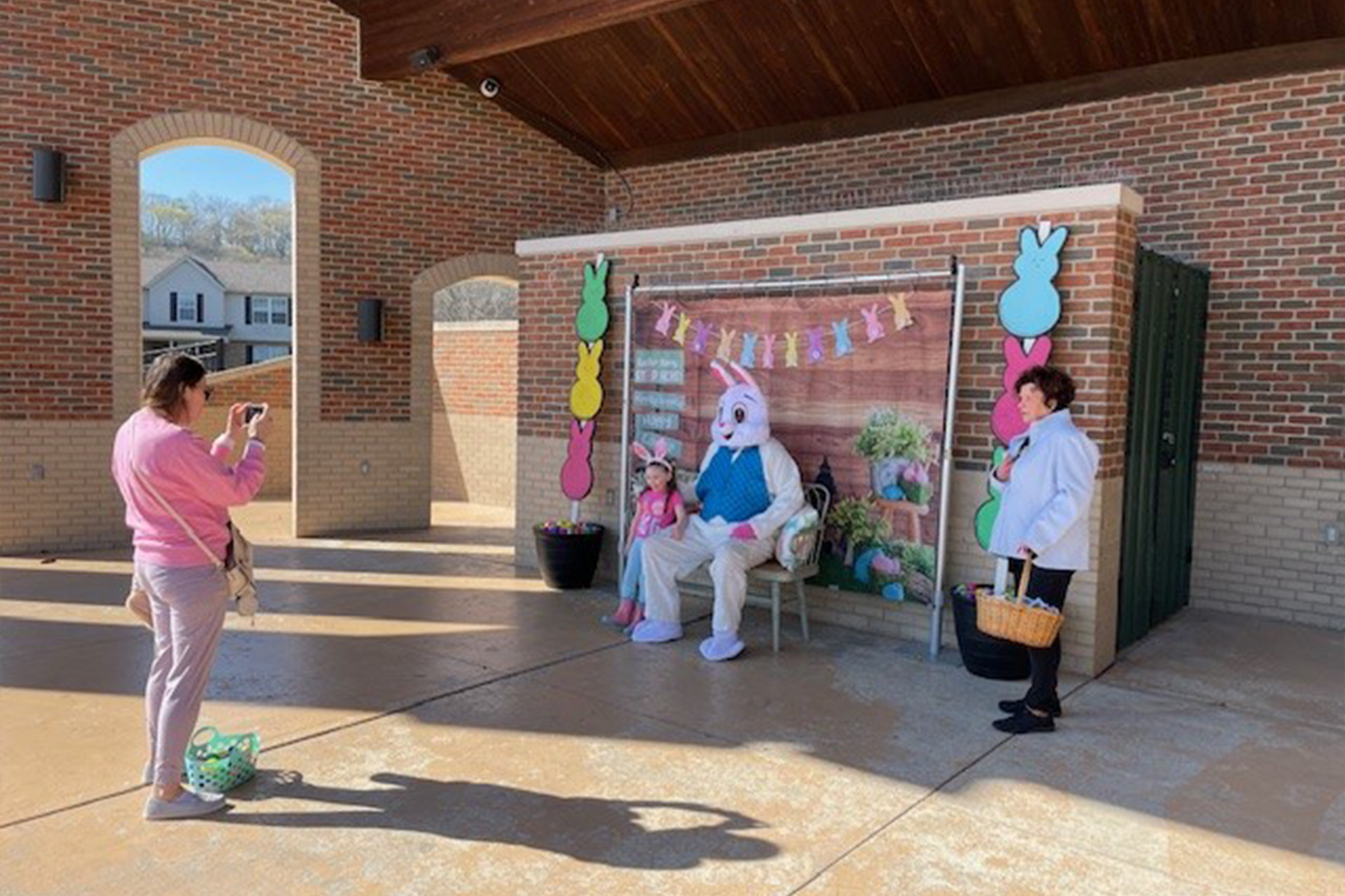 Child sits with Easter Bunny as an adult takes a photo at a spring event
