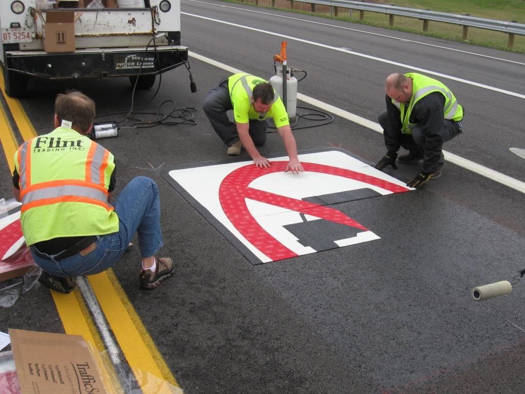 Fairfield's resident sign craftsmen, Wes and Jason, install the pre-formed thermoplastic pavement markings for No Thru Trucks in the lanes that lead to Ross Road