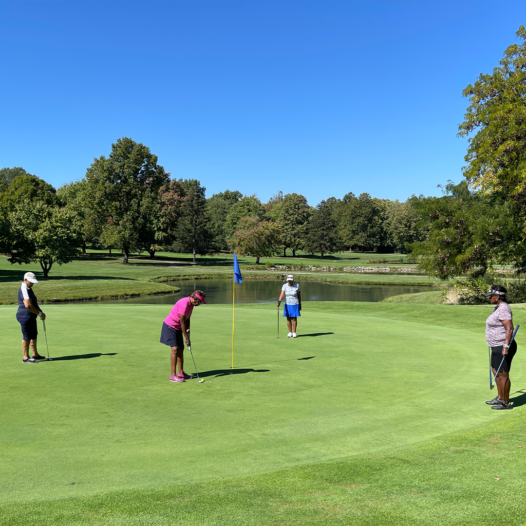Four women putting on the green. 