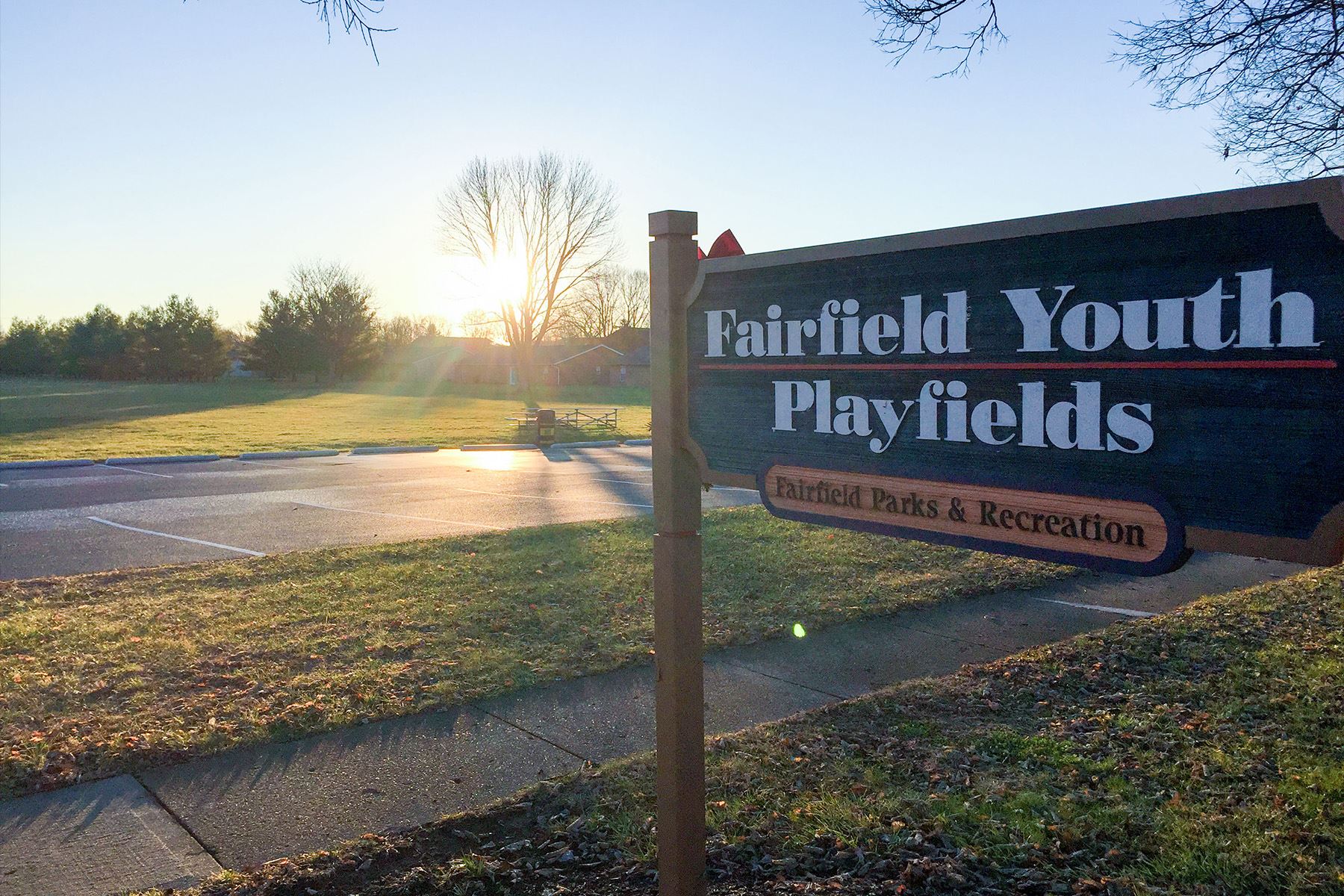 Fairfield Youth Playfields sign at sunrise with open fields in the background.