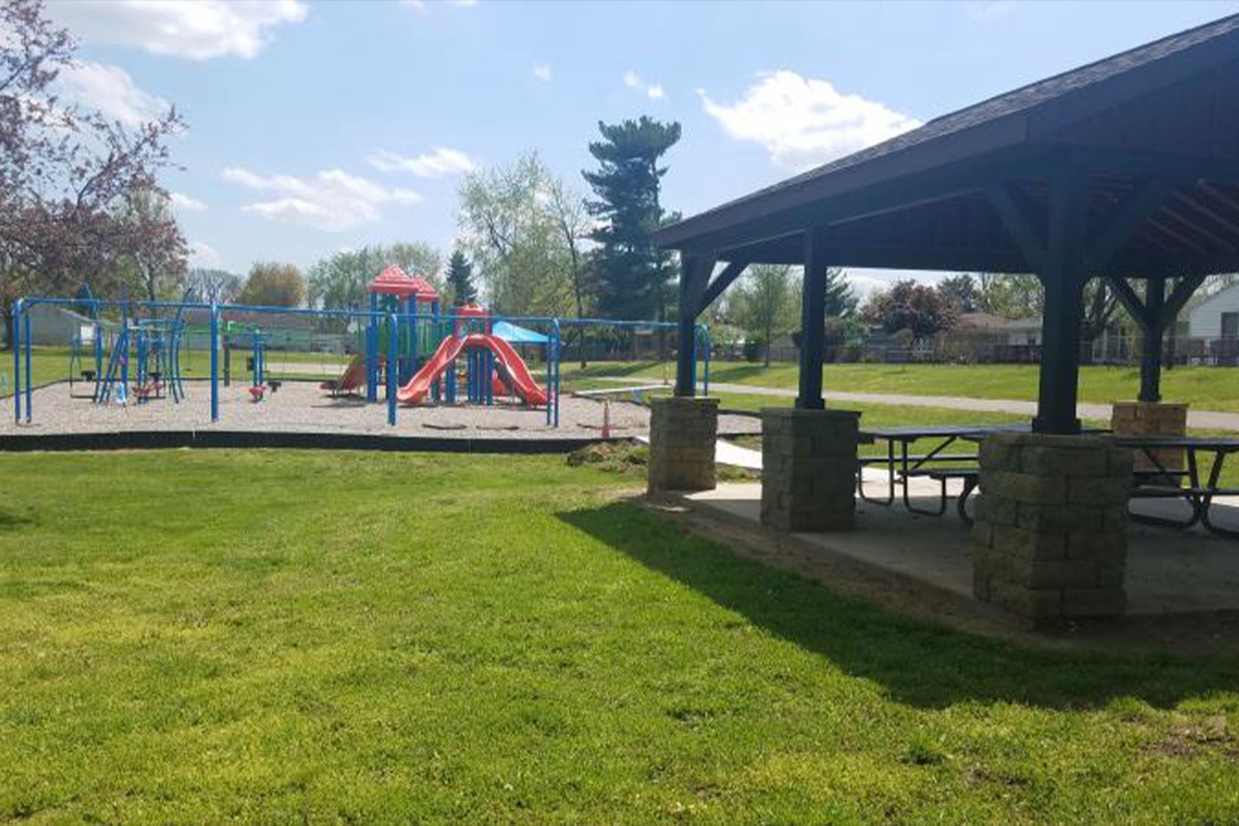 Playground and picnic pavilion at Good Neighbors Park on a sunny day.