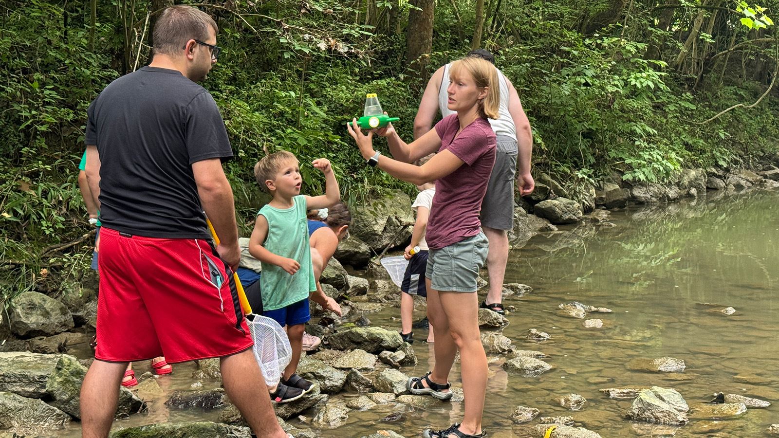 Families explore a creek while learning about wildlife with a naturalist.